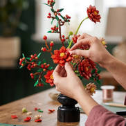 A close-up of hands carefully arranging a Mavirea building block flower into a black vase, showcasing its intricate detail as an eternal, decorative gift.