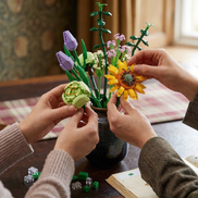 Two people collaboratively arranging a vibrant bouquet of Mavirea building block flowers, including sunflowers and purple tulips, into a dark vase for personalized home decor.