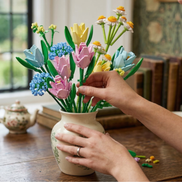 A person arranging a colorful bouquet of Mavirea building block flowers into a classic ceramic vase, demonstrating how these 