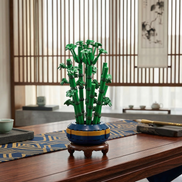 A Mavirea Gourd Bamboo Bonsai building set displayed on a traditional wooden tea table with a geometric blue runner, showcasing a Zen-inspired home decor aesthetic with its vibrant green stems and blue-yellow base.