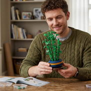 A man smiling while holding the completed Mavirea Gourd Bamboo Bonsai building set, highlighting the product as a satisfying DIY project and a perfect 
