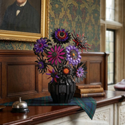 A Mavirea Demon Sunflower building block bouquet in a black architectural vase, styled on a wooden mantelpiece alongside a vintage desk bell and antique books, set against a backdrop of classic portrait art and patterned wallpaper.