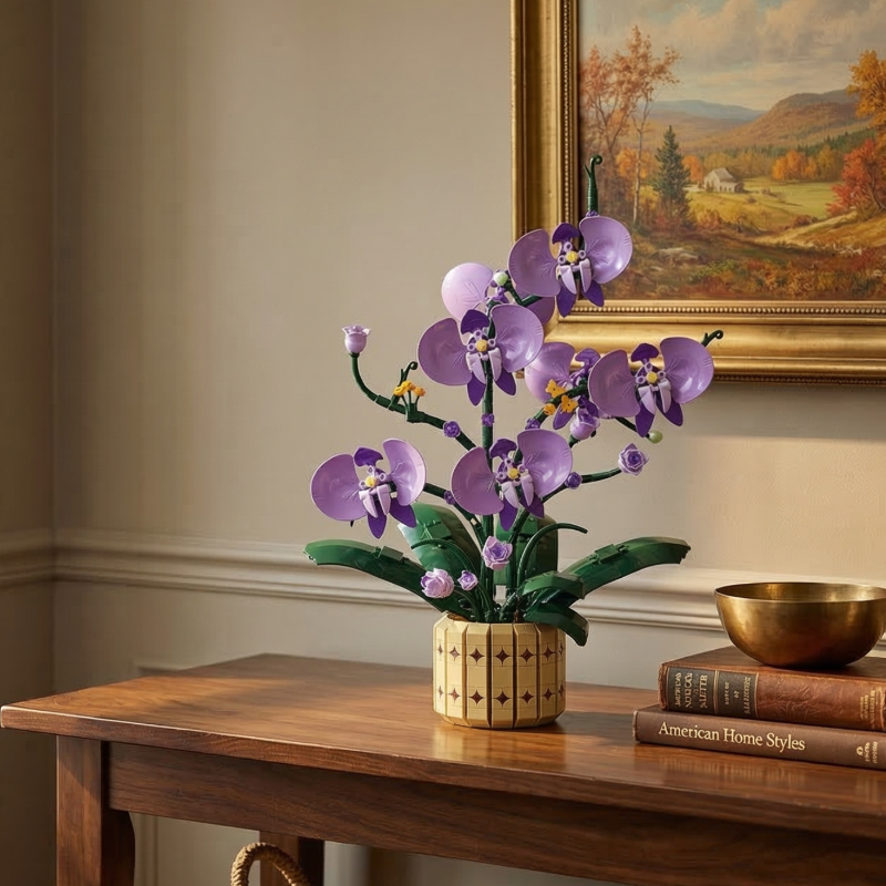 An elegant Mavirea Potted Moth Orchid building set displayed on a wooden console table next to a gold bowl and vintage books, creating a sophisticated home decor accent against a classic landscape painting.