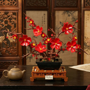 A centered view of the Mavirea Plum Blossom Potted centerpiece on a traditional tea table, paired with a clay teapot and an ornate wooden screen for a classic, timeless home ornament.