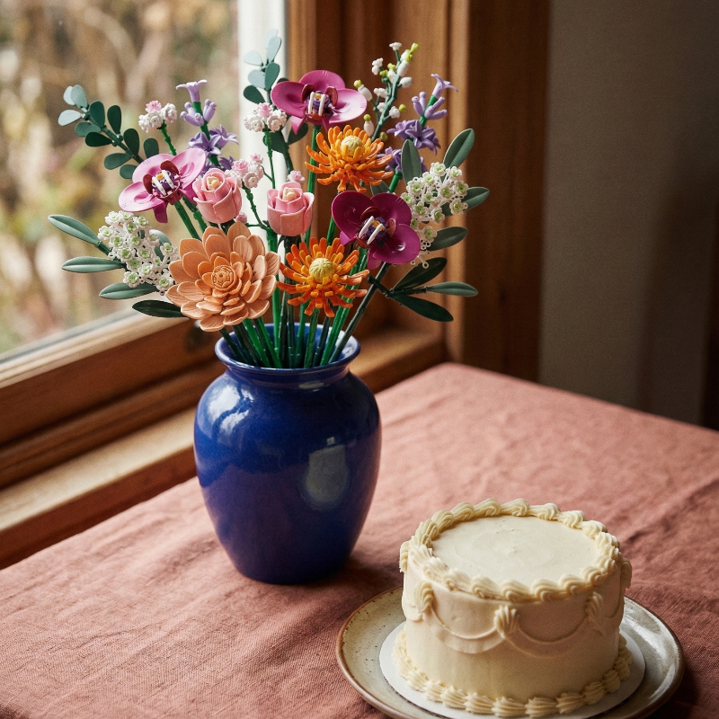 A Mavirea bouquet in a vibrant cobalt blue vase paired with an elegant cake, perfect for a celebratory and eternal home decor setup.
