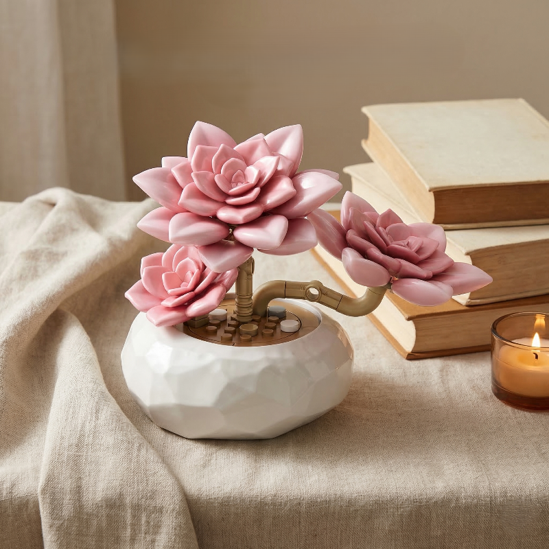 Mavirea pink succulent building blocks on a linen tablecloth with a candle and books, capturing a warm and eternal floral gift aesthetic.