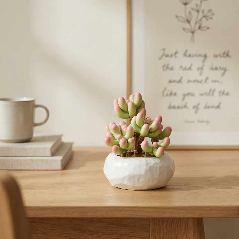 Mavirea green and pink "jelly bean" succulent building blocks on a modern wooden desk, adding a touch of everlasting greenery to a workspace.