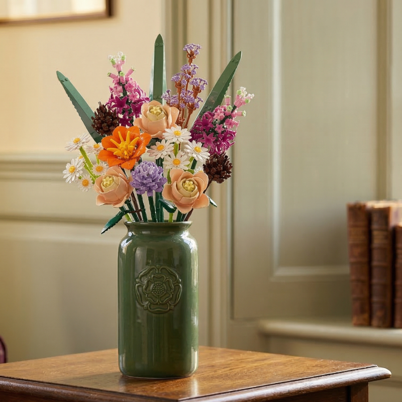 A vibrant Mavirea Whispering Pines Floral building block set displayed in a sage green embossed vase, featuring a mix of daisies, peach roses, and purple blooms to create an elegant home decor centerpiece.