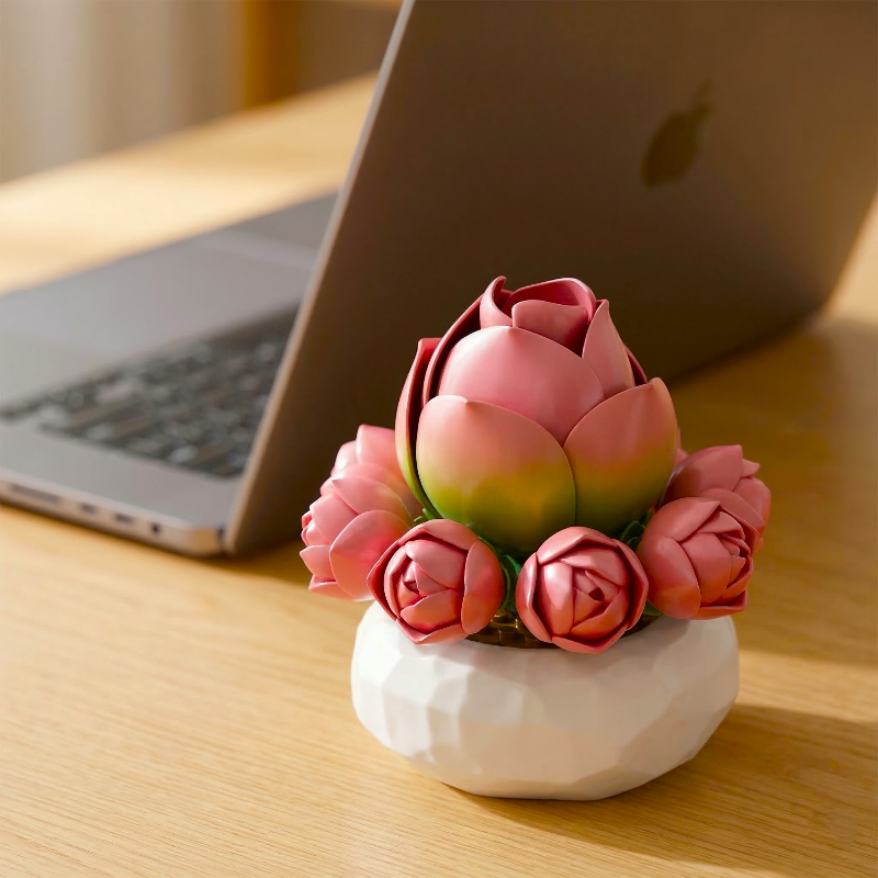 A Mavirea's rose succulent sitting beside a laptop on a wooden desk, offering a touch of everlasting greenery to a modern workspace.